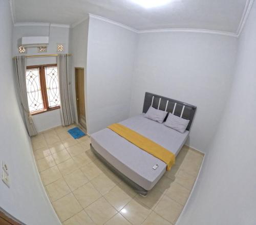 1 dormitorio con 1 cama en una habitación blanca en Nitikan Stay Homestay Jogja, en Timuran