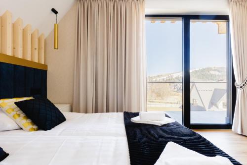 a bedroom with a large bed and a large window at Góralski Resort Family & SPA in Białka Tatrzanska
