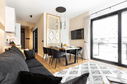 a living room with a couch and a table with chairs at Góralski Resort Family & SPA in Białka Tatrzanska