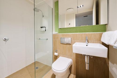 a bathroom with a toilet and a sink and a shower at Abode Gungahlin in Canberra