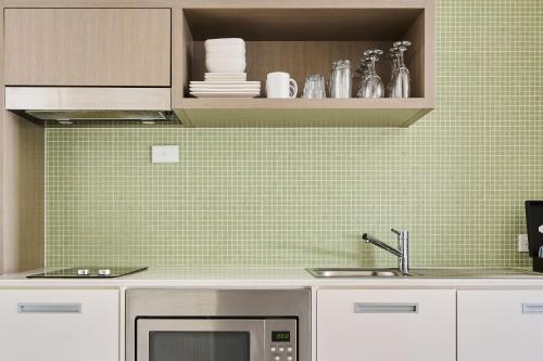 a kitchen with a sink and a microwave at Abode Gungahlin in Canberra