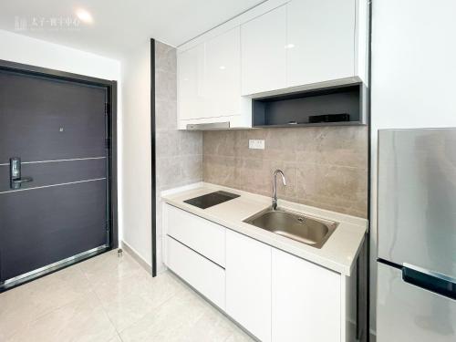 a white kitchen with a sink and a refrigerator at Prince Huan Yu Center Hotel & Residence太子寰宇中心酒店公寓 in Phnom Penh