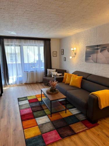 a living room with a black couch and a colorful rug at Weidach Zentrum 1 in Leutasch