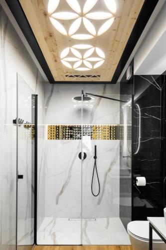 a bathroom with a shower with black and white tiles at Góralski Resort Family & SPA in Białka Tatrzanska