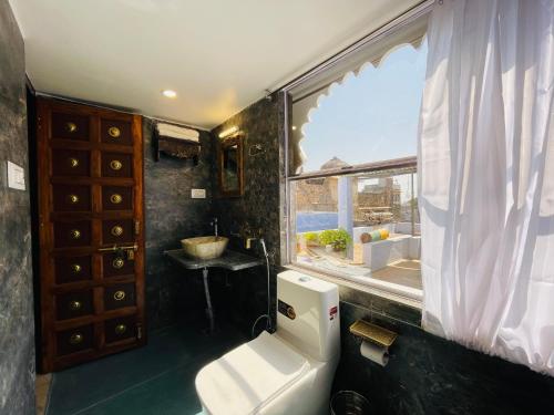a bathroom with a toilet and a window at The Castle View Homestay in Būndi