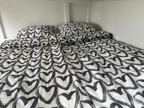 a bed with a black and white bedspread with hearts at Luxus Tiny House Saagala in Tornio
