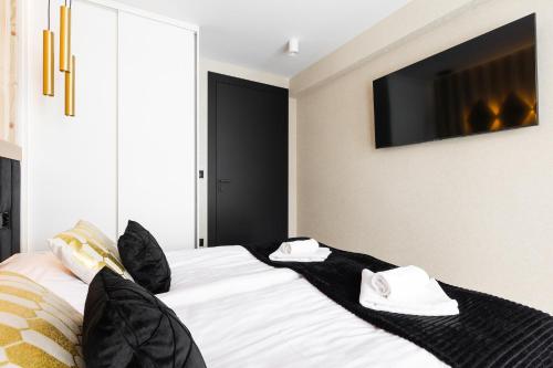 a bedroom with a bed with black pillows and a tv at Góralski Resort Family & SPA in Białka Tatrzanska
