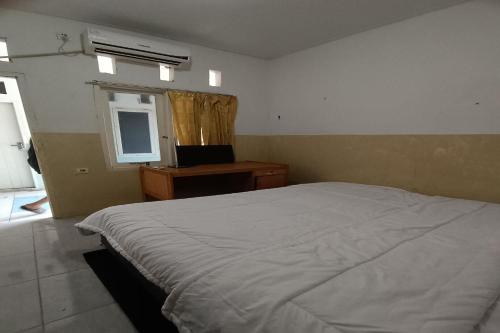 1 dormitorio con cama blanca y ventana en OYO 93207 Merah House, en Pekanbaru