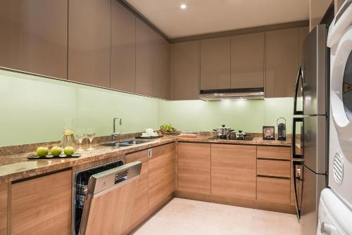 a kitchen with wooden cabinets and stainless steel appliances at Ascott Bonifacio Global City Manila in Manila