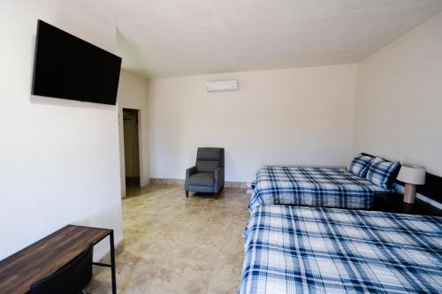 um quarto com duas camas e uma televisão e uma cadeira em HOTEL & RV PARK ROSA EVELYN em San Quintín