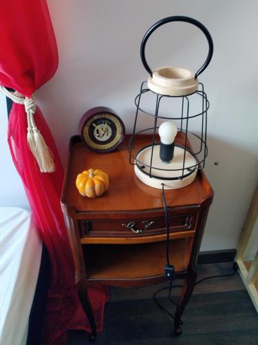 a nightstand with a lamp and pumpkins on it at Le Petit Gite des sorciers in Chitray