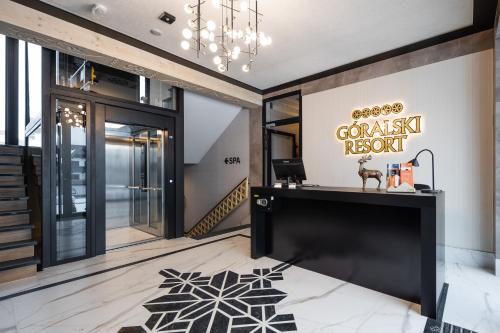 a lobby with a black counter and a chandelier at Góralski Resort Family & SPA in Białka Tatrzanska