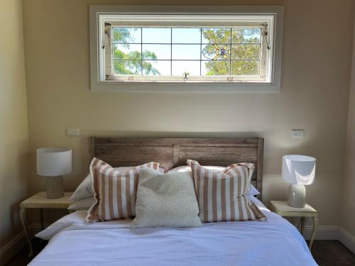 a bedroom with a bed with a window above it at Byron Sunset Cottage in Ewingsdale