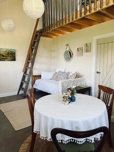 a room with a table with a bed and a staircase at Byron Sunset Cottage in Ewingsdale