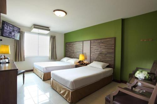 a hotel room with two beds and green walls at Rambuttri Village Plaza in Bangkok
