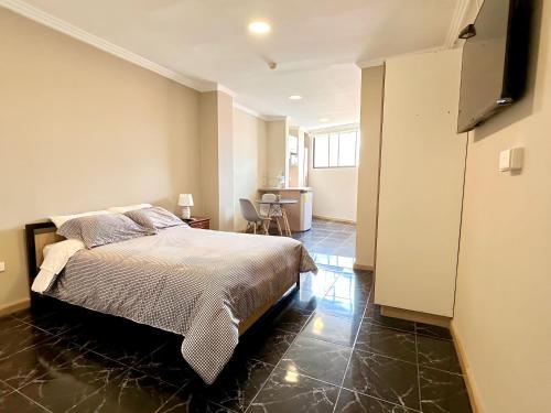 a bedroom with a bed and a room with a kitchen at Suitesecu Cuenca in Cuenca