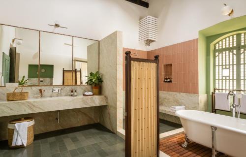 a bathroom with a tub and a sink and a bath tub at Casa Desa Monteiro 4BHK Stand Alone Villa In Diwar Island with Complementary Breakfast & Private Pool, Garden, Fully Equipped Kitchen in Divar