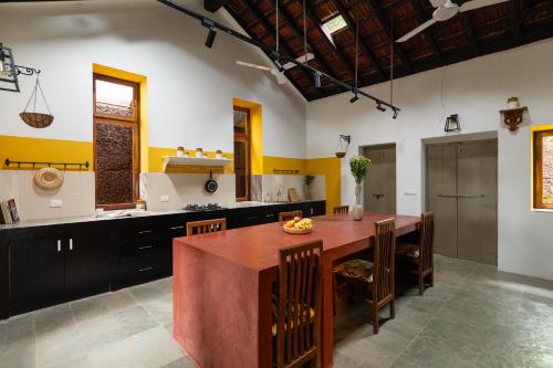 a large kitchen with a wooden table and chairs at Casa Desa Monteiro 4BHK Stand Alone Villa In Diwar Island with Complementary Breakfast & Private Pool, Garden, Fully Equipped Kitchen in Divar
