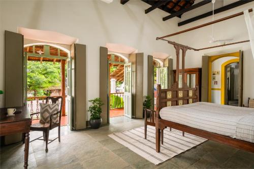 a bedroom with a bed and a desk and windows at Casa Desa Monteiro 4BHK Stand Alone Villa In Diwar Island with Complementary Breakfast & Private Pool, Garden, Fully Equipped Kitchen in Divar