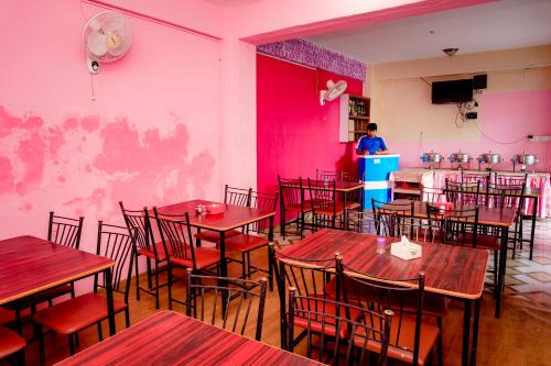 a restaurant with tables and chairs and a person in a kitchen at Hotel Peace Stupa in Pokhara