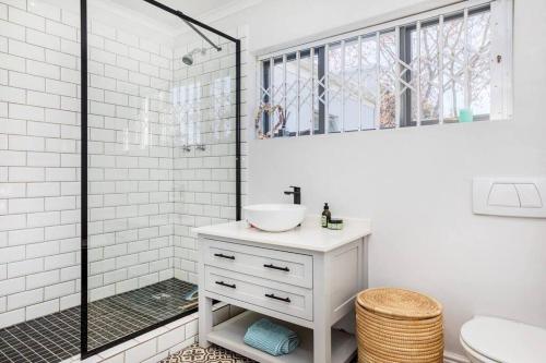 a white bathroom with a sink and a shower at Maroon Belles in Cape Town