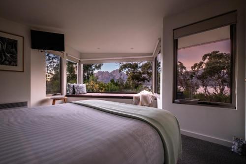 a bedroom with a bed and a large window at Driftwood in Coles Bay