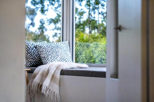a window with a blanket on a bench in front of it at Driftwood in Coles Bay