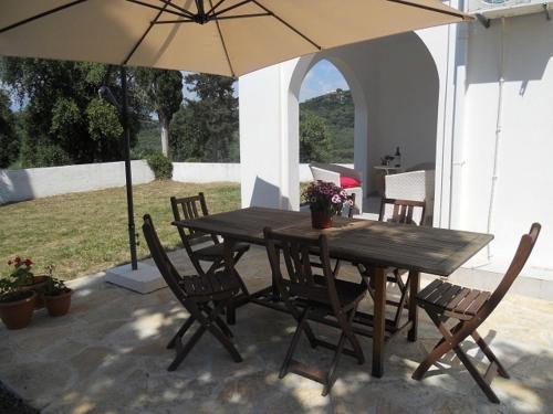 a wooden table and chairs with an umbrella at Villa Fedrita in Acharavi