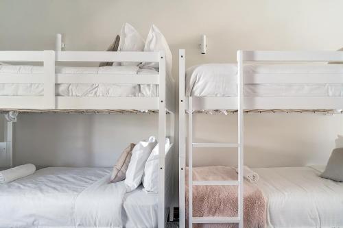 a bedroom with white bunk beds with a ladder at Southbeach - Direct Beach Access To Jones Beach in Kiama Downs