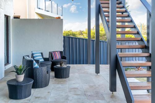 a patio with two wicker chairs and a staircase at Southbeach - Direct Beach Access To Jones Beach in Kiama Downs