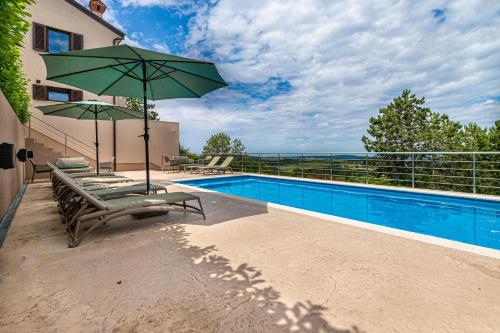 a swimming pool with two lounge chairs and an umbrella at Luxury Pool Villa Gradin - Happy Rentals in Gračišče