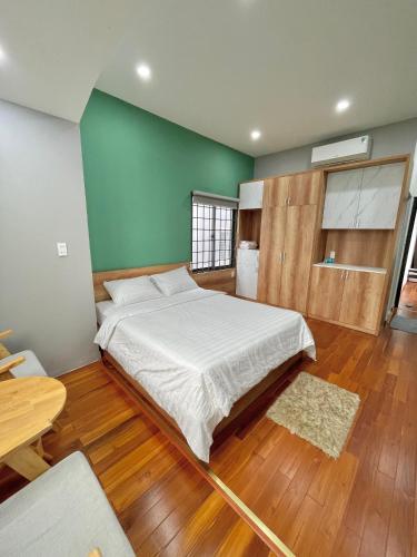 a bedroom with a large bed and a green wall at POTA Hotel & Apartment in Da Nang