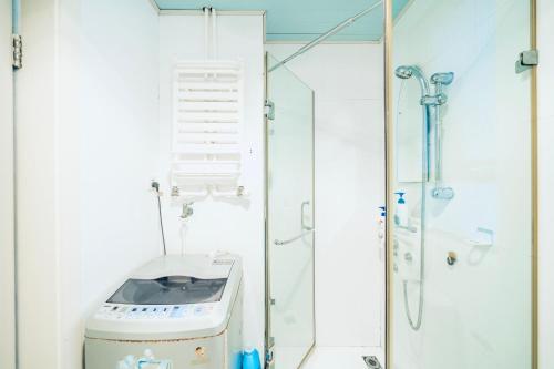 uma casa de banho com um chuveiro e uma máquina de lavar roupa em Shanghai New International Expo Center Hanzhiju Apartment em Xangai