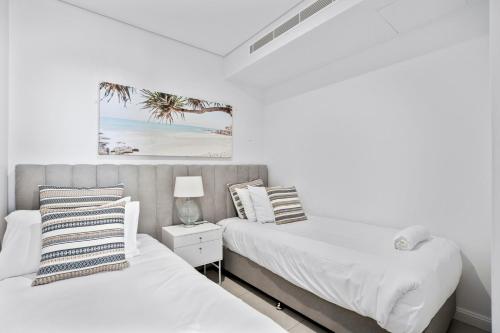 two beds in a room with white walls at Ocean Surfers Paradise - gclr in Gold Coast