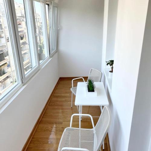 a white table and chairs in a room with windows at BeoCity 011 in Novi Beograd
