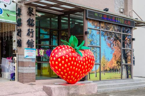 a large red strawberry statue in front of a store at Quan Ming B&B in Dahu