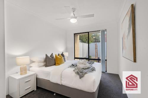 a white bedroom with a bed and a window at Bunbury Beach Splendor: Where Dolphins Dance in Bunbury