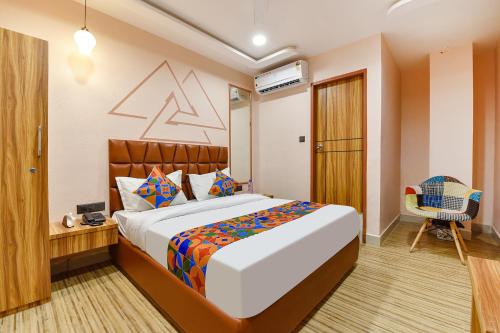 a bedroom with a large bed and a chair at FabHotel The Palace in Vadodara