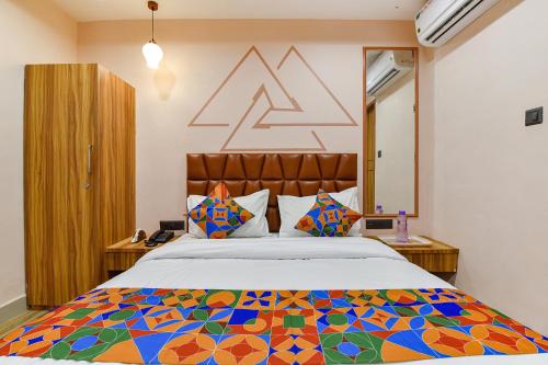 um quarto com uma cama grande e um edredão colorido em FabHotel The Palace em Vadodara