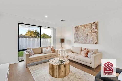 a living room with two couches and a table at Bunbury Beach Splendor Modern Coastal Home in Bunbury