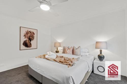 a white bedroom with a bed with a blanket on it at Bunbury Beach Splendor Modern Coastal Home in Bunbury