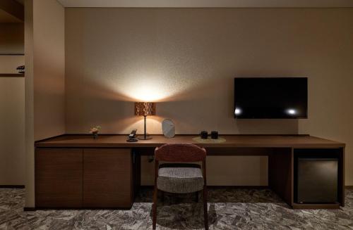 a desk with a television and a chair in a hotel room at Minn Kanazawa in Kanazawa