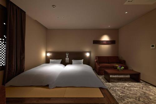 a bedroom with a large white bed and a couch at Minn Kanazawa in Kanazawa