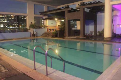 a large swimming pool at a hotel at night at Studio Suite beside Greenbelt Mall Makati City in Manila