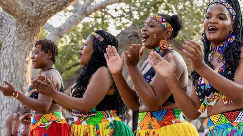 a group of girls in colorful costumes standing in front of a tree at Lindiwe Safari Lodge in Hoedspruit