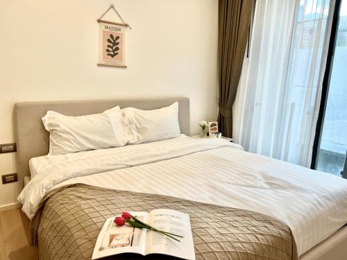 een slaapkamer met een bed met een boek en bloemen erop bij Circle Sukhumvit 11#Luxury#Pool#Gym#BTS Nana&MRT Sukhumvit#1BR#Max2ppl in Bangkok