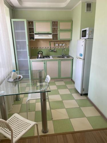 a kitchen with a glass table and a refrigerator at Юбилейный in Almaty