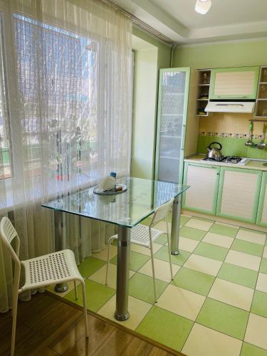 a kitchen with a glass table in a kitchen at Юбилейный in Almaty