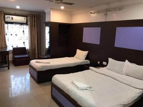 a hotel room with two beds and a chair at HOTEL SHIVA in Guwahati