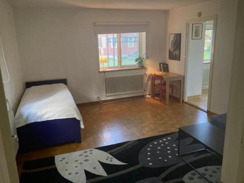 1 dormitorio con cama, mesa y ventana en Lägenhet i lugn trädgård, en Bygdeå